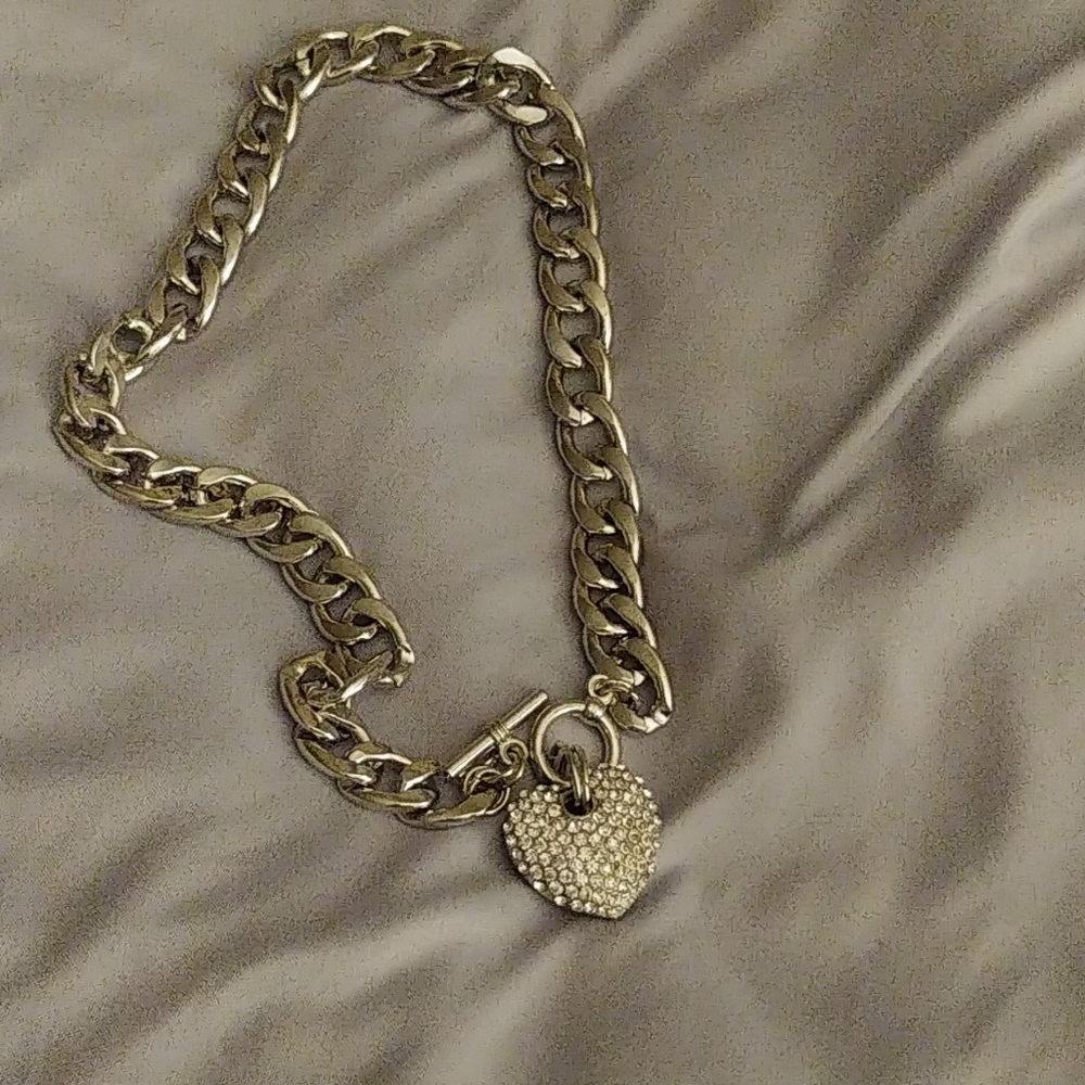 A silver chain link necklace with a heart